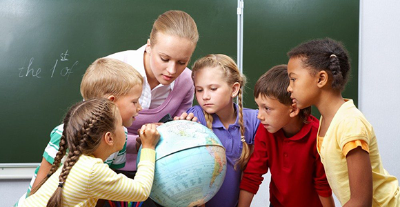 Children being taught about the globe by a female teacher